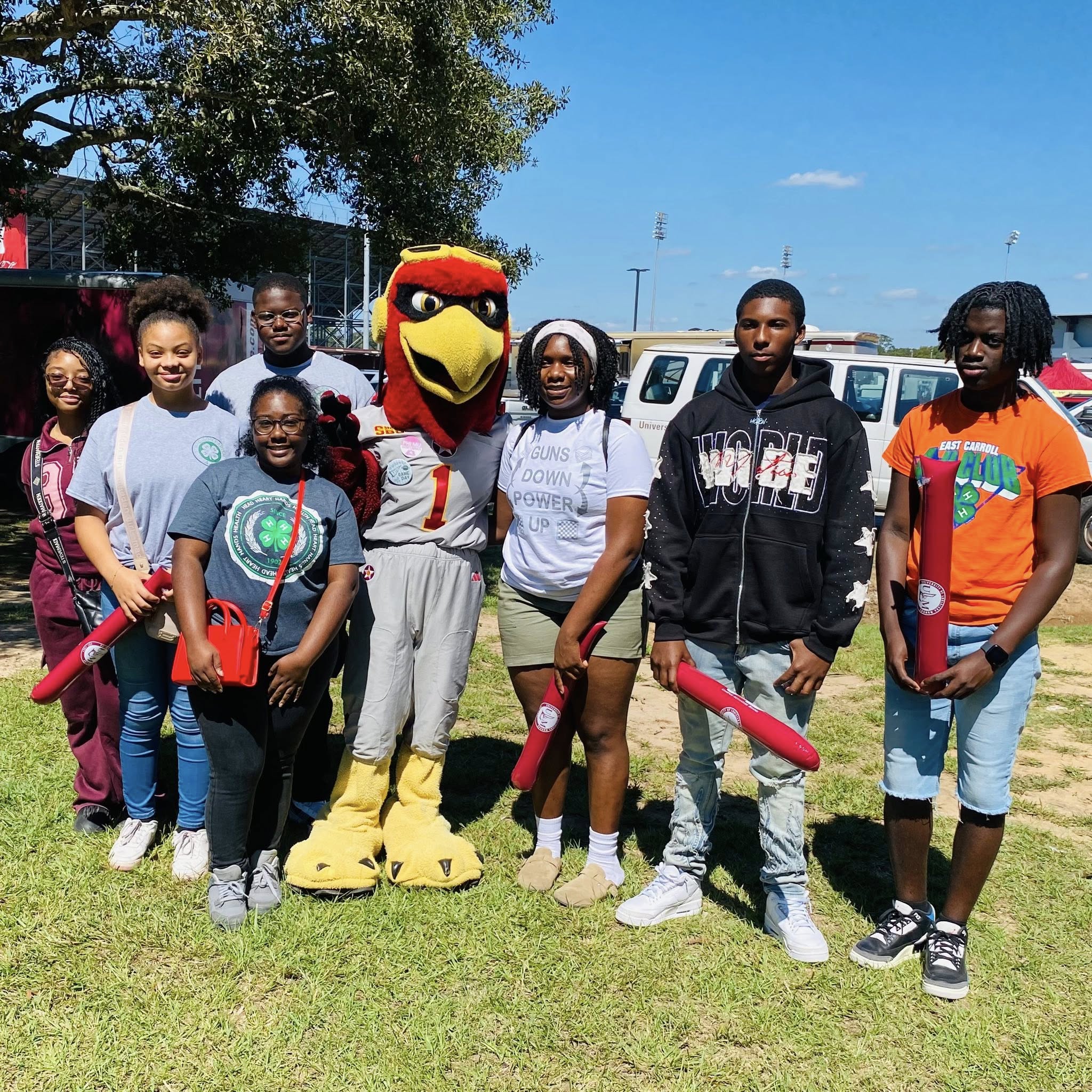 Some teenagers posing with a sports mascot.